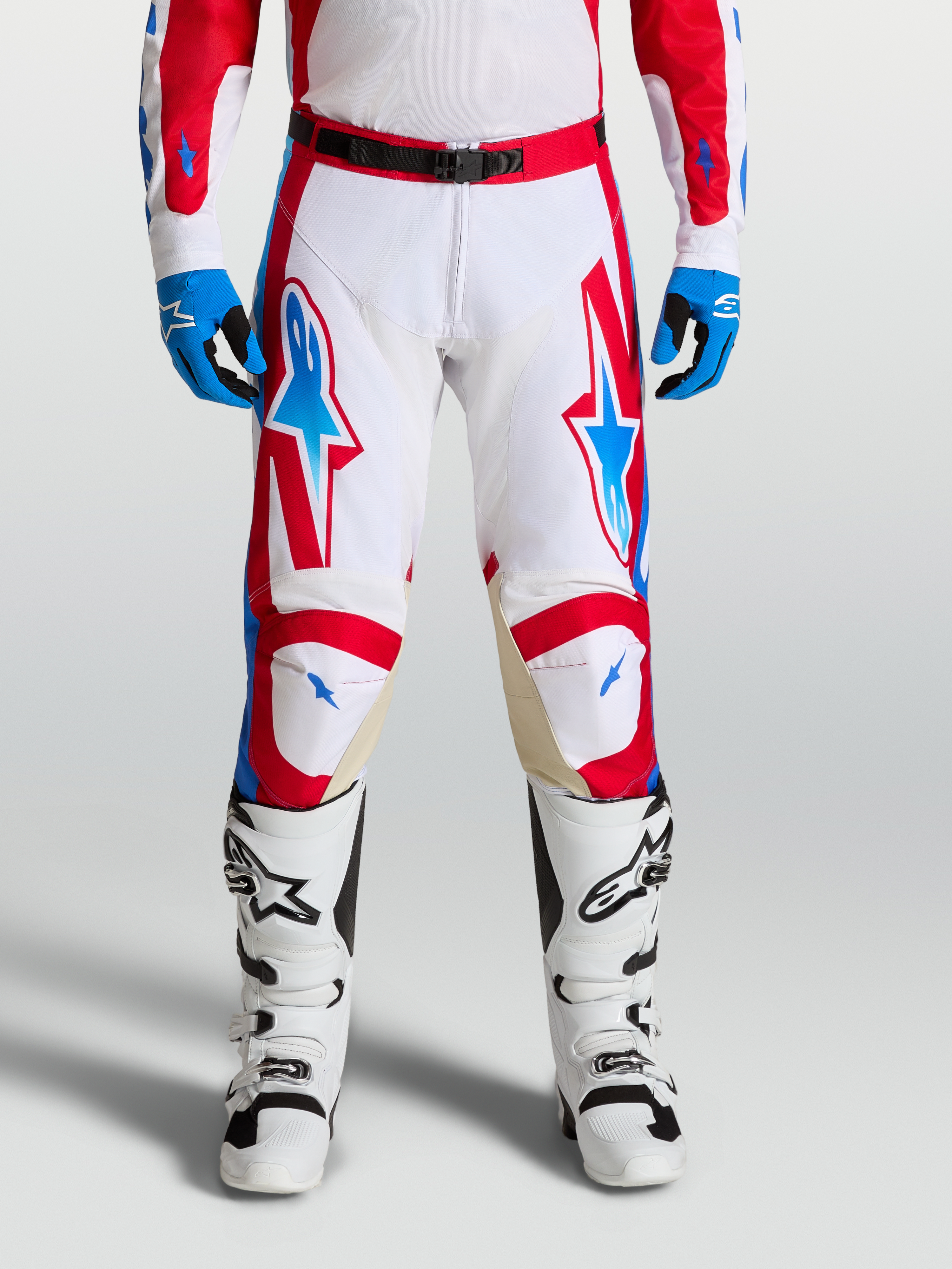 Alpinestars Racer Hose Hunt, Motocross-Hose in Weiß, Rot und Blau, on-model getragen mit Stiefeln, ergonomische Passform und Ziegenleder-Knieeinsätze.