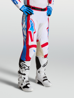 Alpinestars Racer Hose Hunt, Motocross-Rennsport-Hose in Weiß, Rot und Blau mit ergonomisch vorgekrümmten Beinen und Leder-Innenknien, getragen mit Tech 7 Motocross-Stiefeln.
