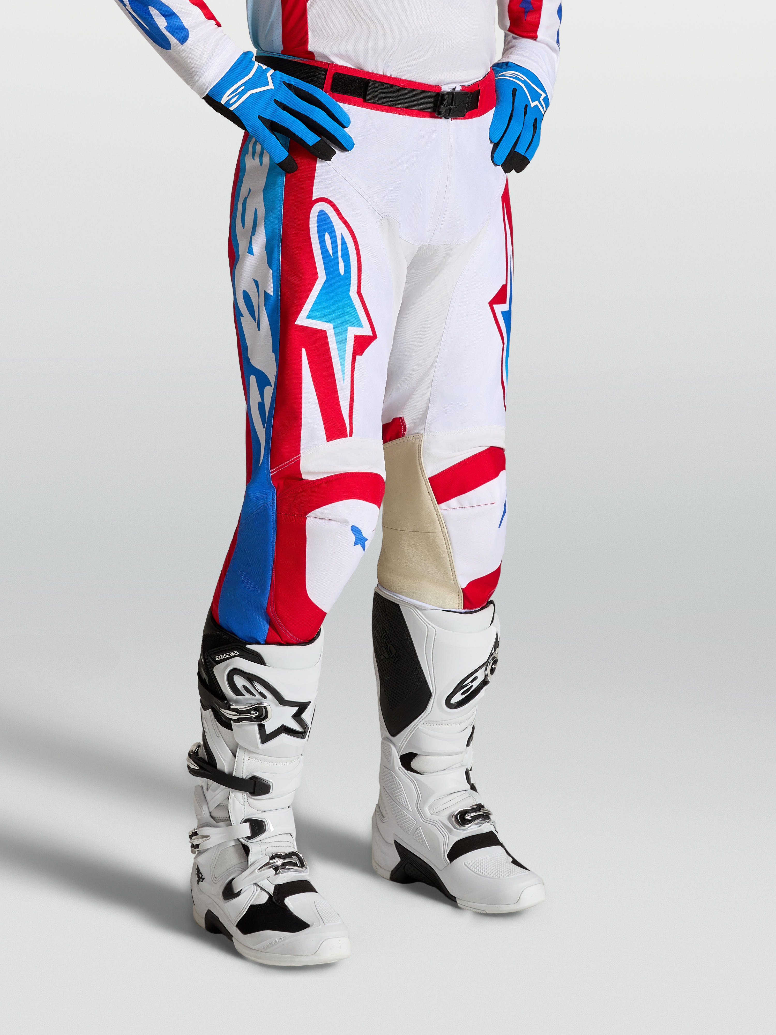 Alpinestars Racer Hose Hunt, Motocross-Rennsport-Hose in Weiß, Rot und Blau mit ergonomisch vorgekrümmten Beinen und Leder-Innenknien, getragen mit Tech 7 Motocross-Stiefeln.
