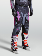 Alpinestars Racer Lone Hose für Herren, Motocross-Hose im Grau-Camo-Design mit Pinken Akzenten, 600D Polyfabric-Konstruktion, getragen mit passenden Trikot und Tech 10 Stiefeln für Offroad-Performance.