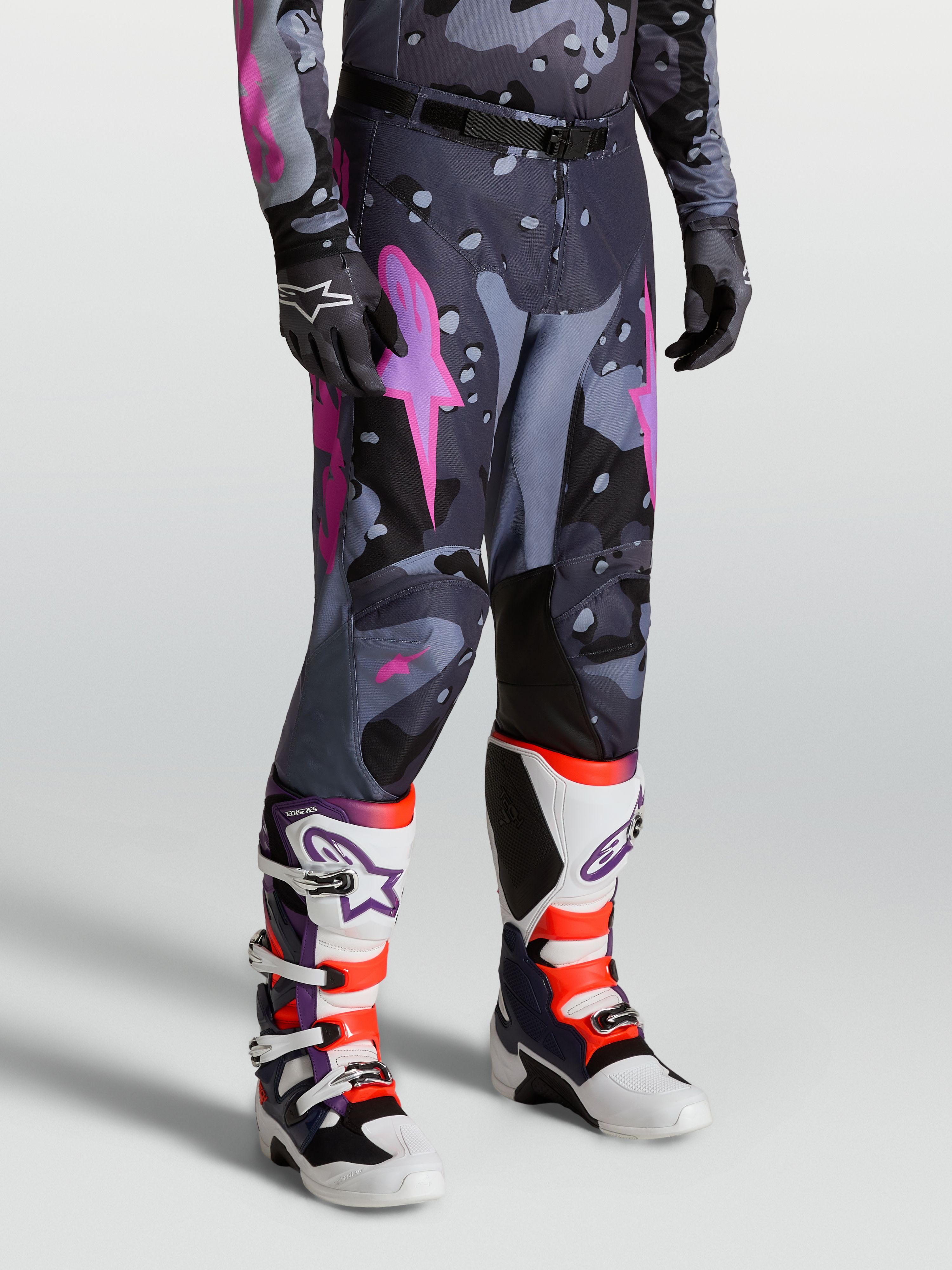 Alpinestars Racer Lone Hose für Herren, Motocross-Hose im Grau-Camo-Design mit Pinken Akzenten, 600D Polyfabric-Konstruktion, getragen mit passenden Trikot und Tech 10 Stiefeln für Offroad-Performance.