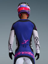 Rear view of a motocross rider wearing the 2026 Techstar Knif Jersey in Black Light Gray Purple, featuring a purple back panel with a pink Alpinestars logo, light gray sleeves with black accents and laser-cut perforations, coordinated with a matching pink and purple helmet and black gloves.