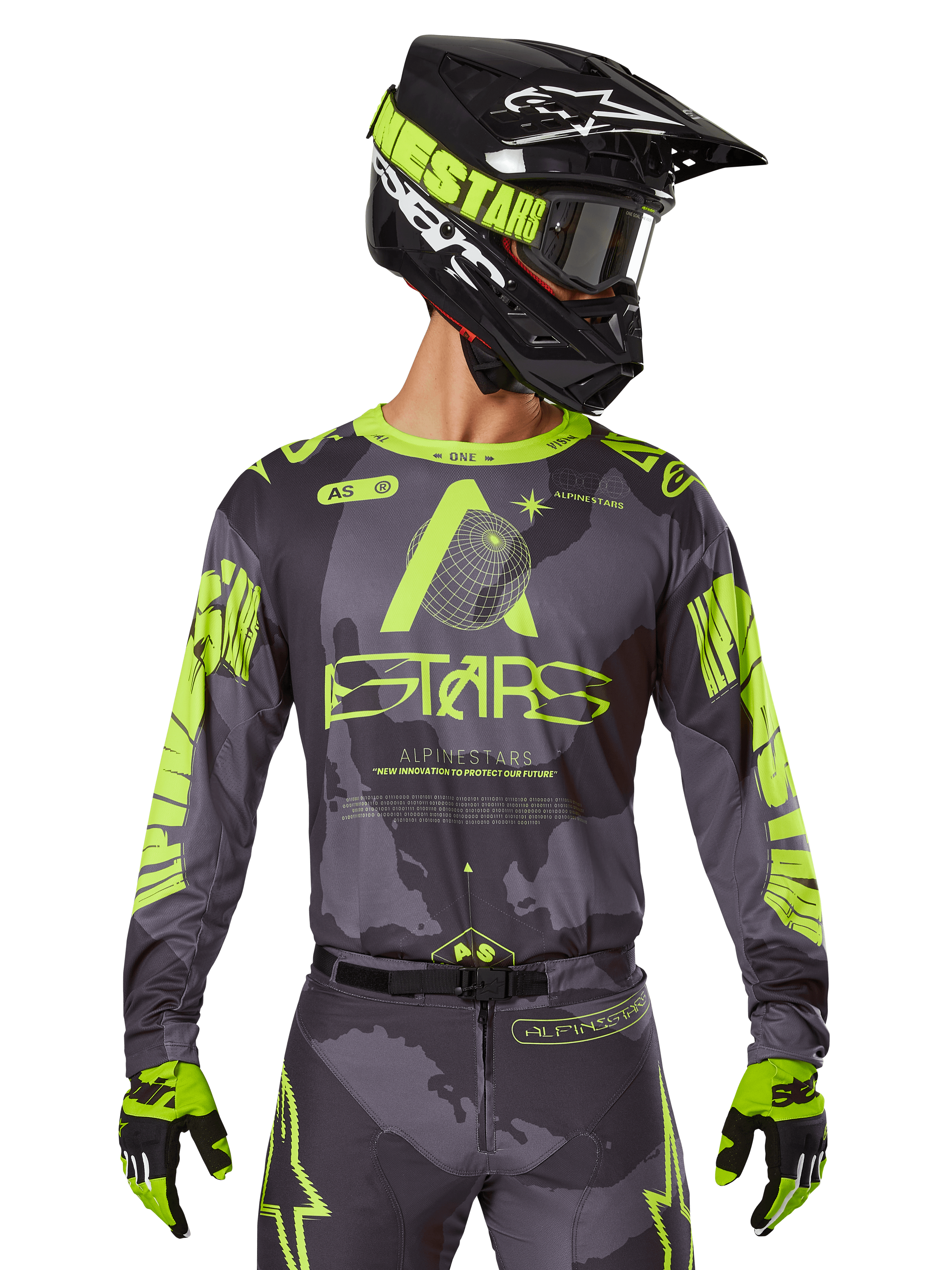 Alpinestars 2025 Racer Hollow Trikot, Motocross-Renntrikot, Dunkles Camo und Neongelb, getragen mit passender Hose, schwarz-gelbem Helm mit Brille und schwarzen Handschuhen, mit Alpinestars-Branding und Camouflage-Design