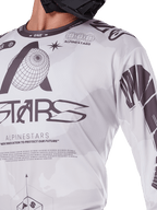 Nahaufnahme des Alpinestars 2025 Racer Hollow Jerseys, Weiß und Grau, mit schwarzen Grafikdrucken, Globus-Logo und Binärcode, technische Motocross-Bekleidung für das Gelände