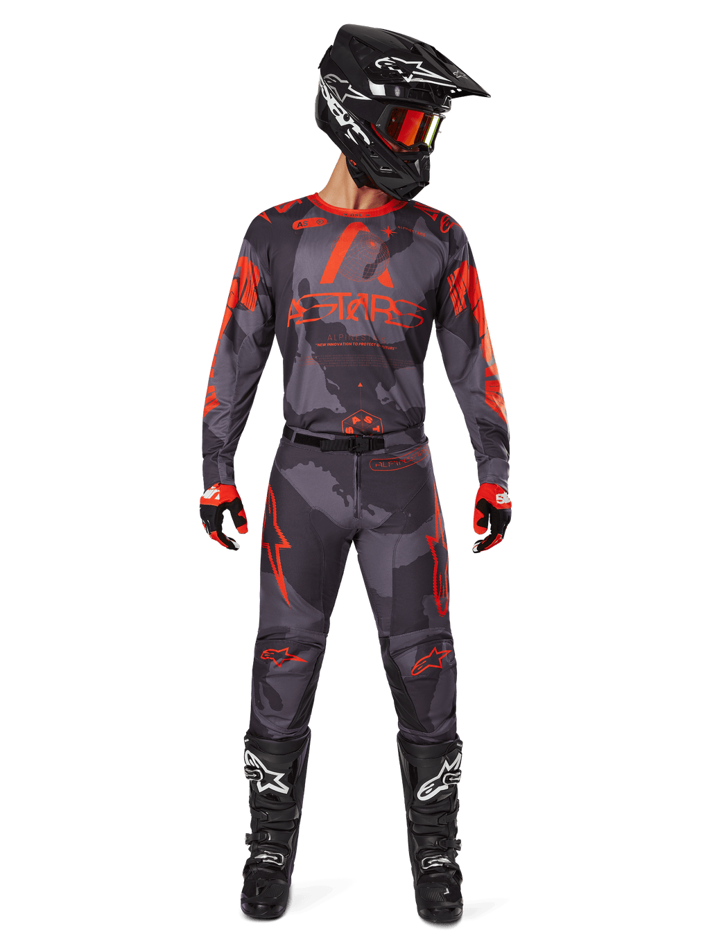 Motocross-Fahrer mit Alpinestars 2025 Racer Hollow Trikot und passender Hose in Grau Camo Orange Fluo, komplette Ausrüstung mit schwarzem Helm, Goggles, Handschuhen und Stiefeln, markante orangefarbene Logos und Camouflage-Muster.