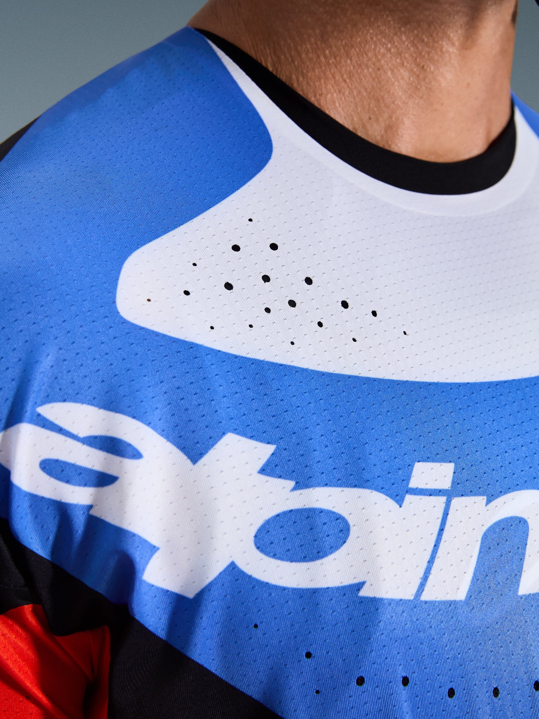 Alpinestars 2026 Techstar Knif Jersey, Motocross-Jersey, Nahaufnahme von Brust und Hals, Blau und Weiß mit schwarzem Kragen, lasergeschnittene Belüftungslöcher, atmungsaktives Mesh-Gewebe mit Alpinestars-Logo.