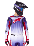 Alpinestars 2025 Fluid Wurx Trikot, Motocross-Rennsport-Trikot, lila-weißer Farbverlauf, rotes Sternenlogo und Akzente, athletische Passform, getragen mit passender Hose, schwarzem Helm und roten Handschuhen