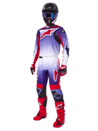 Motocross-Fahrer im Alpinestars 2025 Fluid Wurx Gear Set, lilafarbenes und leuchtend rotes Trikot mit weißen Akzenten, passende Motocross-Hose, leuchtend rote Stiefel, schwarzer Helm mit blauer Brille, rot-schwarze Handschuhe, komplette professionelle Offroad-Rennausrüstung