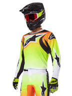 Motocross-Fahrer mit Alpinestars 2025 Fluid Wurx Gear Set, Trikot mit gelb-orangefarbenem Farbverlauf und schwarzen Akzenten, große Stern-Logos, passende Motocross-Hose, schwarzer Fullface-Helm mit rot getönter Brille, gelbe Handschuhe, abgestimmtes Hochleistungs-Outfit für Offroad-Rennen