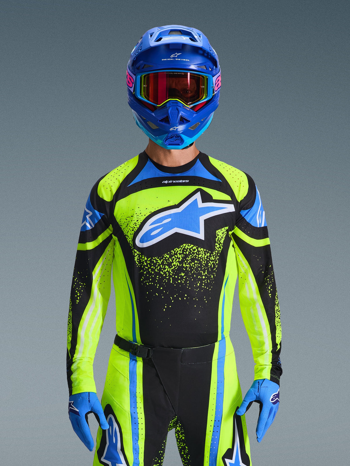 Motocross rider wearing the Alpinestars 2026 Techstar Nomur Jersey in Dark Navy and Yellow Fluo with blue accents, featuring a large blue logo on the chest, matching blue helmet and goggles, coordinated racing gear for off-road competition