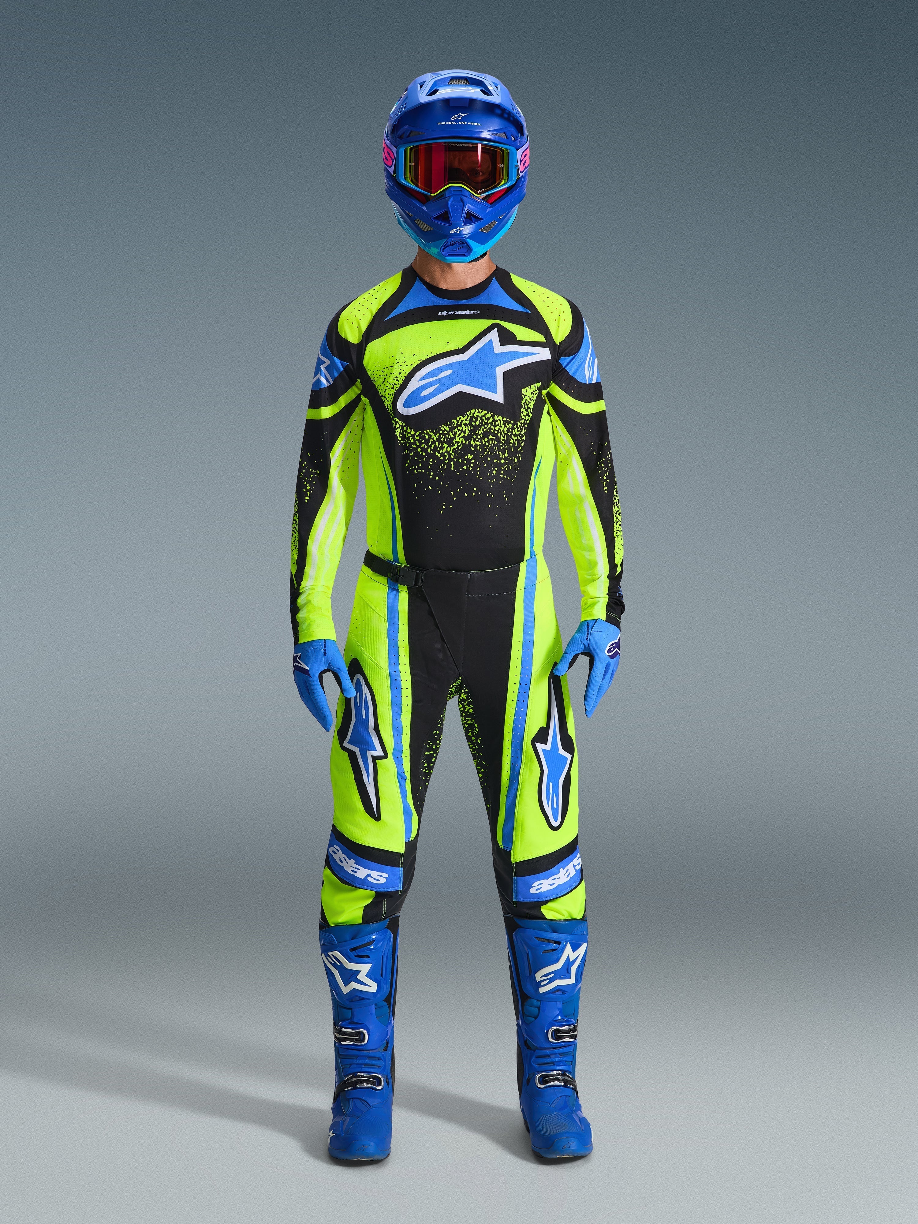 Motocross-Fahrer in kompletter Rennausrüstung, 2026 Techstar Nomur Trikot in Gelb Fluo und Dunkelblau, passende Motocross-Hose, blauer Helm mit rot getönter Brille, blaue Handschuhe und blaue Stiefel, koordiniertes Profi-Outfit für den Offroad-Rennsport