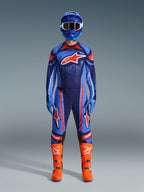 Motocross-Fahrer im Alpinestars 2026 Techstar Nomur Trikot in Dark Navy, Orange und UCLA Blue, kombiniert mit passender Motocross-Hose, blauem Helm mit Goggles und leuchtend orangefarbenen Rennstiefeln, komplett aufeinander abgestimmte Offroad-Wettkampfausrüstung