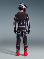 Alpinestars 2026 Fluid Apex Gear Set, Motocross-Fahrer von hinten gesehen, schwarzes Jersey und Hose mit grauen geometrischen Linien und Stern-Logos, schwarzer Helm mit pinkfarbenen Akzenten, leuchtend rote und schwarze Stiefel, abgestimmte Motocross-Rennausrüstung