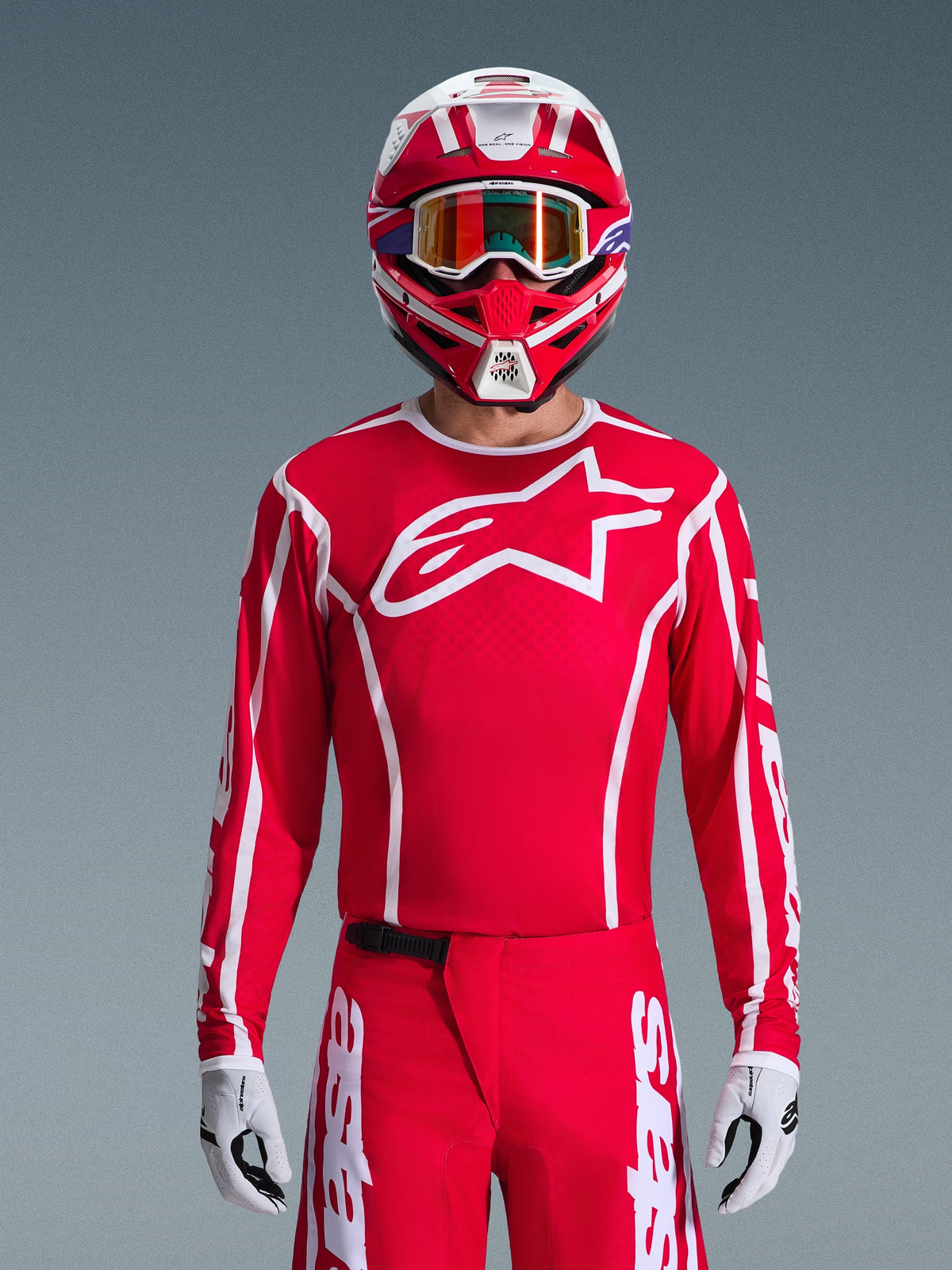 Alpinestars 2026 Fluid Apex Trikot, Motocross-Trikot, Rot und Weiß, getragen von einem Fahrer mit passendem rot-weißem Helm und orangefarbener Brille, mit markantem weißem Logo auf der Brust, sportliche Passform, Teil einer abgestimmten Offroad-Rennausrüstung
