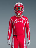 Alpinestars 2026 Fluid Apex Trikot, Motocross-Trikot, Rot und Weiß, getragen von einem Fahrer mit passendem rot-weißem Helm und orangefarbener Brille, mit markantem weißem Logo auf der Brust, sportliche Passform, Teil einer abgestimmten Offroad-Rennausrüstung