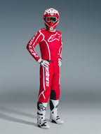Motocross rider wearing the Alpinestars 2026 Fluid Apex Gear Set, Red jersey with large white logos, matching red pants with white branding, white and red helmet, white motocross boots and gloves, coordinated outfit for off-road racing