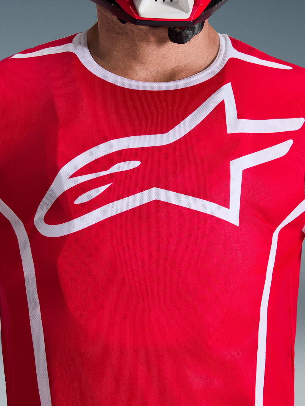 Alpinestars 2026 Fluid Apex Trikot, Rot und Weiß, Nahaufnahme der Brust mit großem weißen Astars-Logo, weißer Sportkragen und feuchtigkeitsableitendes Gewebe für Motocross-Performance
