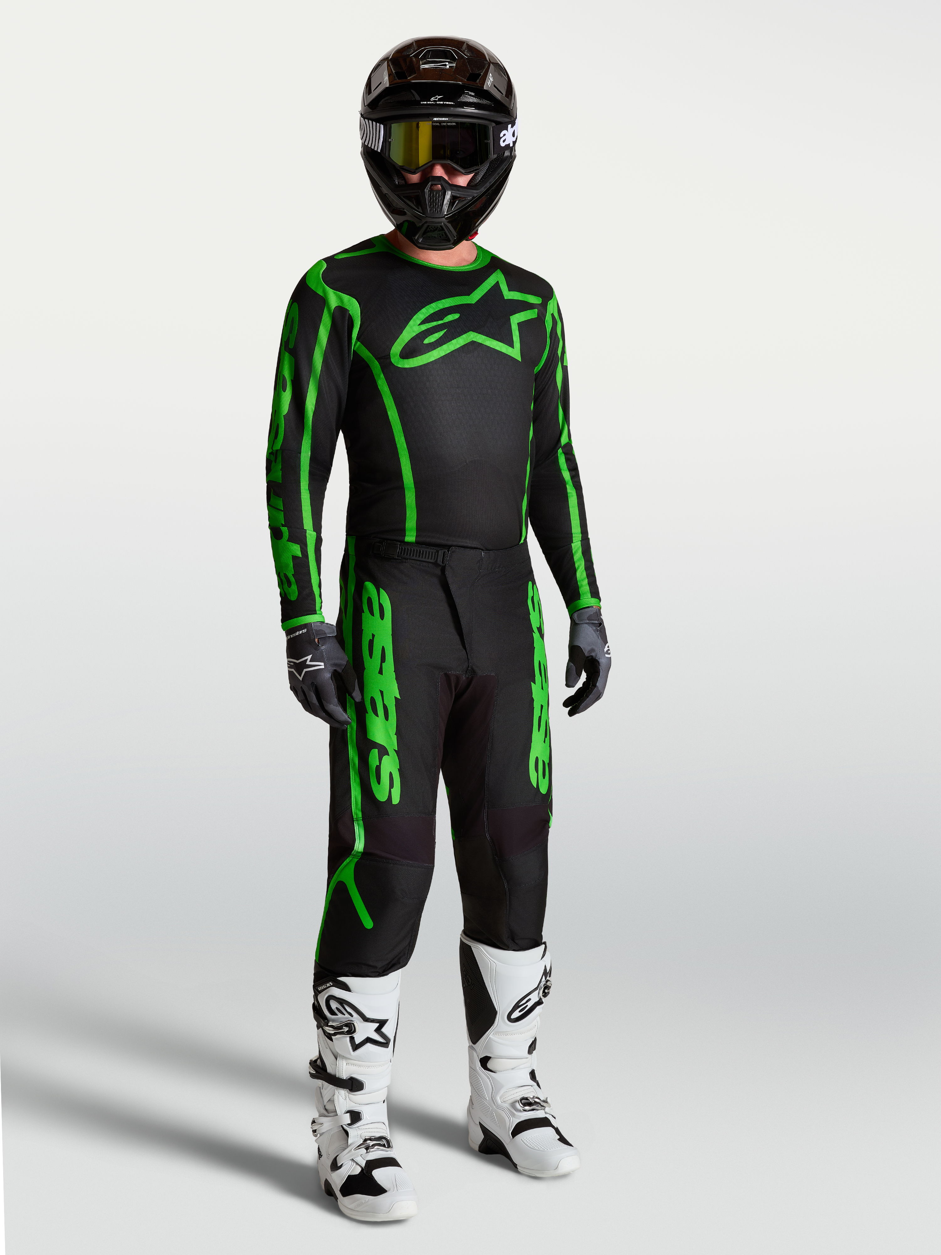 Alpinestars Fluid Apex V2 Hose, Herren-Motocross-Hose, Schwarz und Fluo-Grün, robustes Polygewebe, mit weißen Stiefeln.