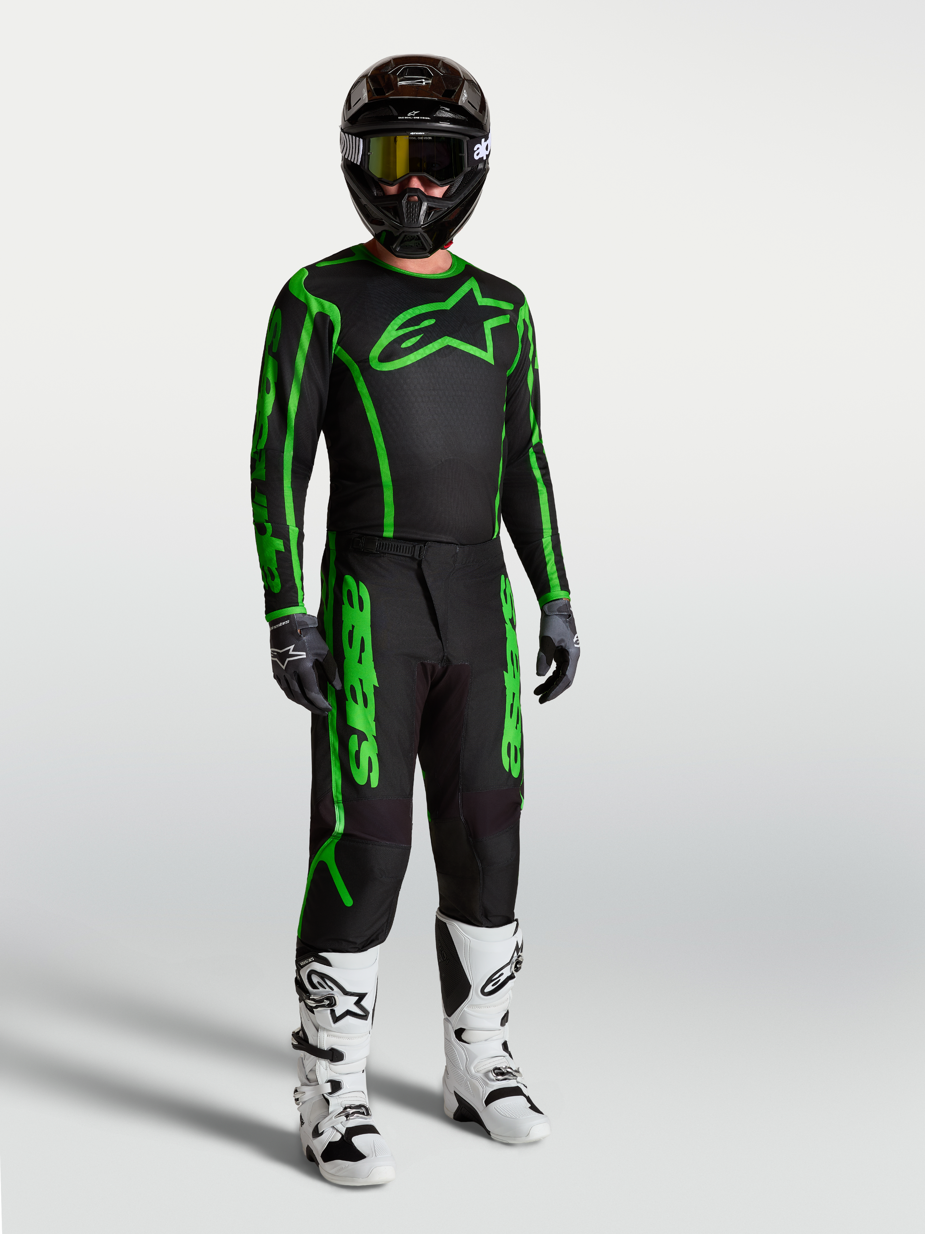 Alpinestars Fluid Apex V2 Trikot, Herren-Motocross-Trikot in Schwarz und Neongrün, am Model mit passender Hose und Stiefeln.