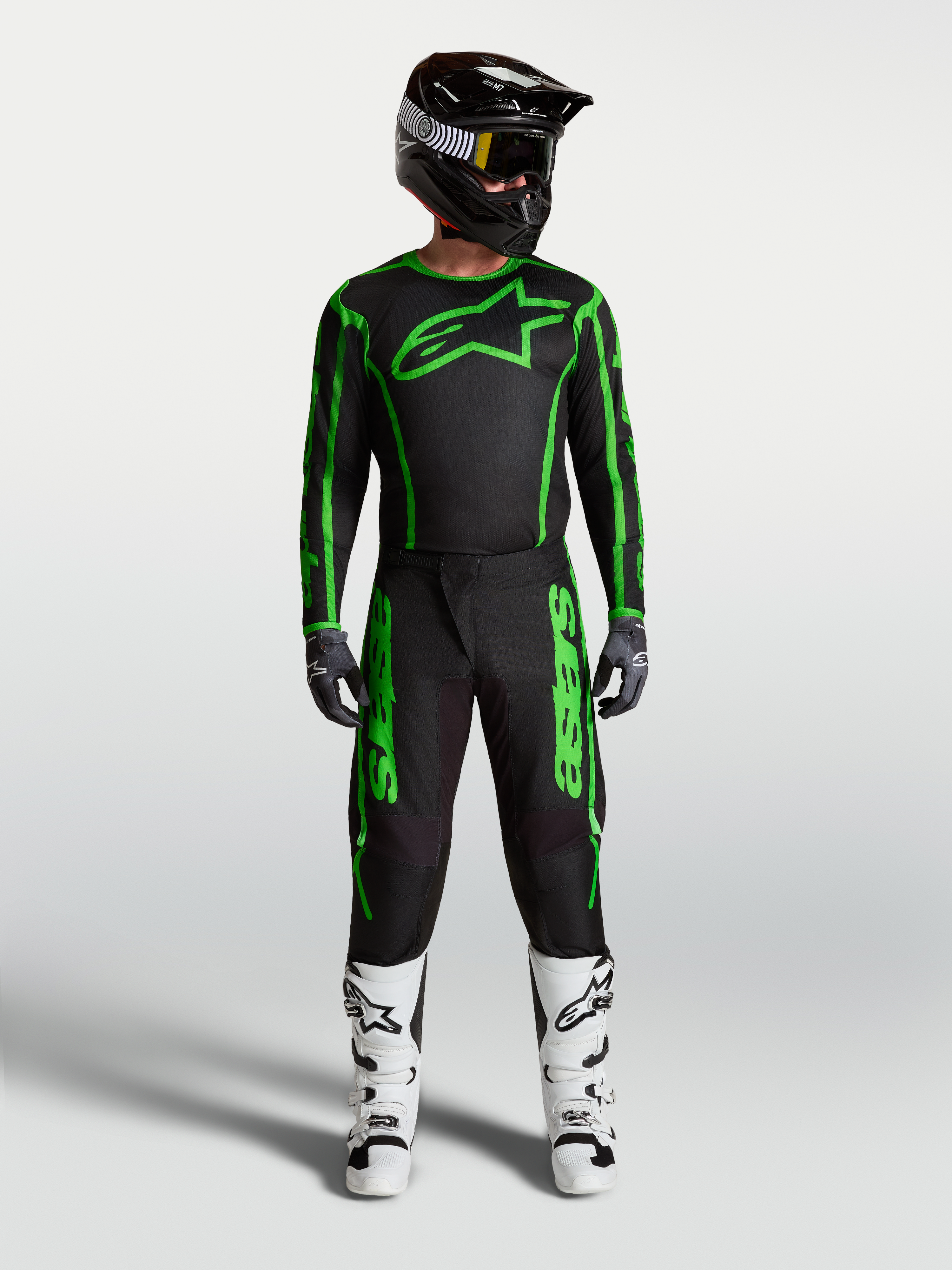 Alpinestars Fluid Apex V2 Trikot und Ausrüstungsset, Herren-Motocross-Outfit in Schwarz und Grün mit weißen Stiefeln.