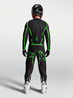 Alpinestars Fluid Apex V2 Hose, Motocross-Hose in Schwarz und Fluo-Grün, Rückansicht am Fahrer mit weißen Motocross-Stiefeln.