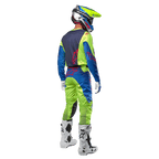 Motocross-Fahrer von hinten im Alpinestars 2024 Racer Hoen Trikot in Gelb Fluo und Blue Night Navy, passende Motocross-Hose und weiße Stiefel, zeigt das Rückendesign mit roten Logos, abgestimmtes Outfit für den professionellen Offroad-Rennsport
