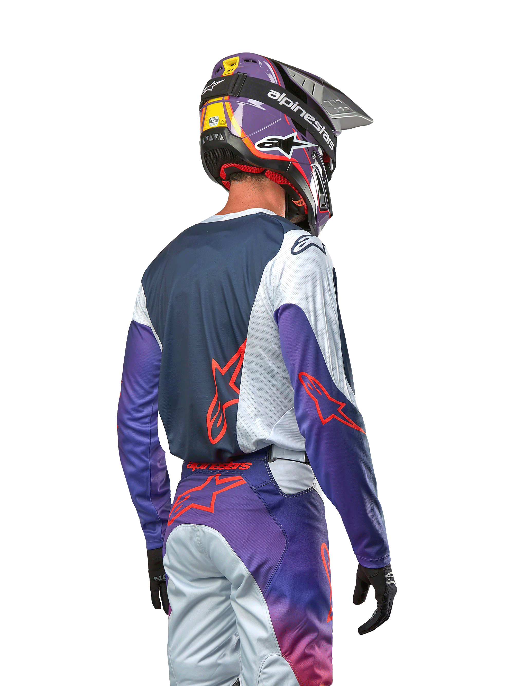 Motocross-Fahrer in der Rückansicht trägt das 2024 Racer Hoen Jersey, dunkelblaues Rückenteil mit hellgrauen Schultern und lila Ärmeln, Alpinestars-Logos in Hot Orange, passende lila-graue Hose mit lila Motocross-Helm, komplette Offroad-Rennausrüstung