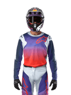 Alpinestars 2024 Racer Hoen Jersey in Hellgrau Hot Orange Schwarz, Motocross-Trikot getragen von einem Fahrer mit passender Ausrüstung, mit einem lebhaften Farbgradienten und dem Alpinestars Stern-Logo auf der Brust, entwickelt für Offroad-Performance.