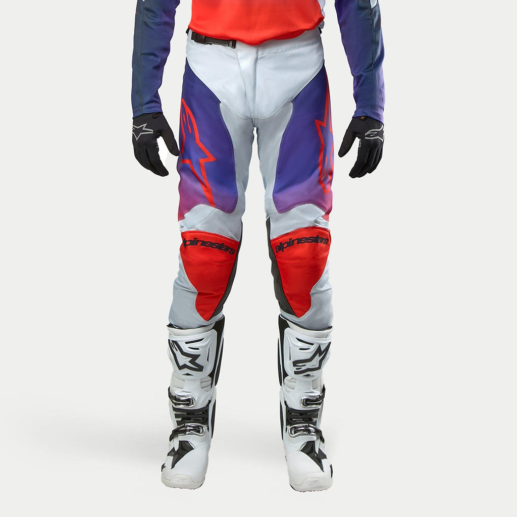 Alpinestars 2024 Racer Hoen Hose, Motocross-Hose, Hellgrau mit Hot Orange, Schwarz und Violett, ergonomisches Design, Teil einer Motocross-Ausrüstung mit weißen Stiefeln und schwarzen Handschuhen, Performance-Offroad-Bekleidung