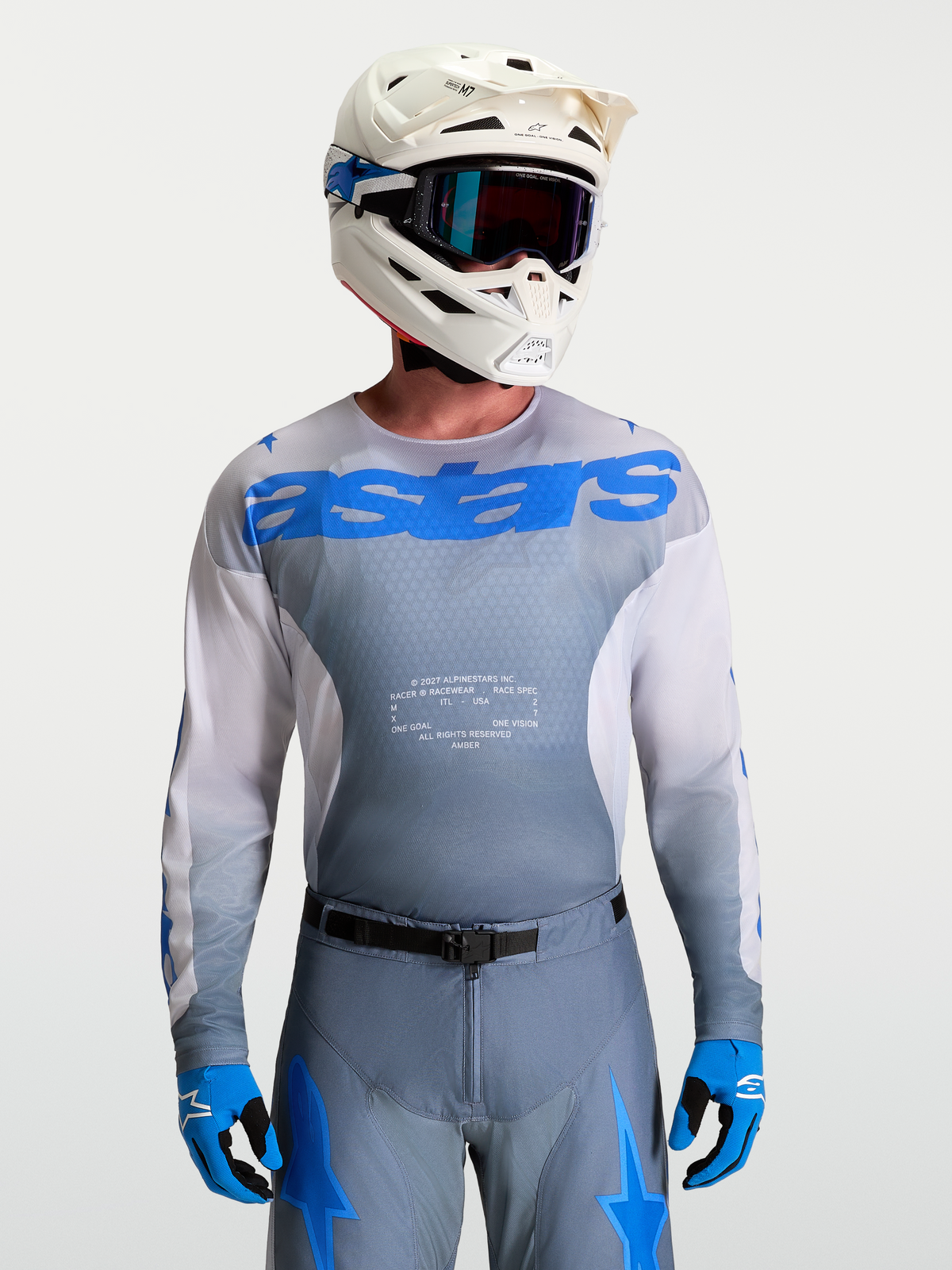Alpinestars Racer Amber Trikot, Motocross-Ausrüstung für Herren, Grau und UCLA Blau, mit weißem MX-Helm und Schutzbrille.