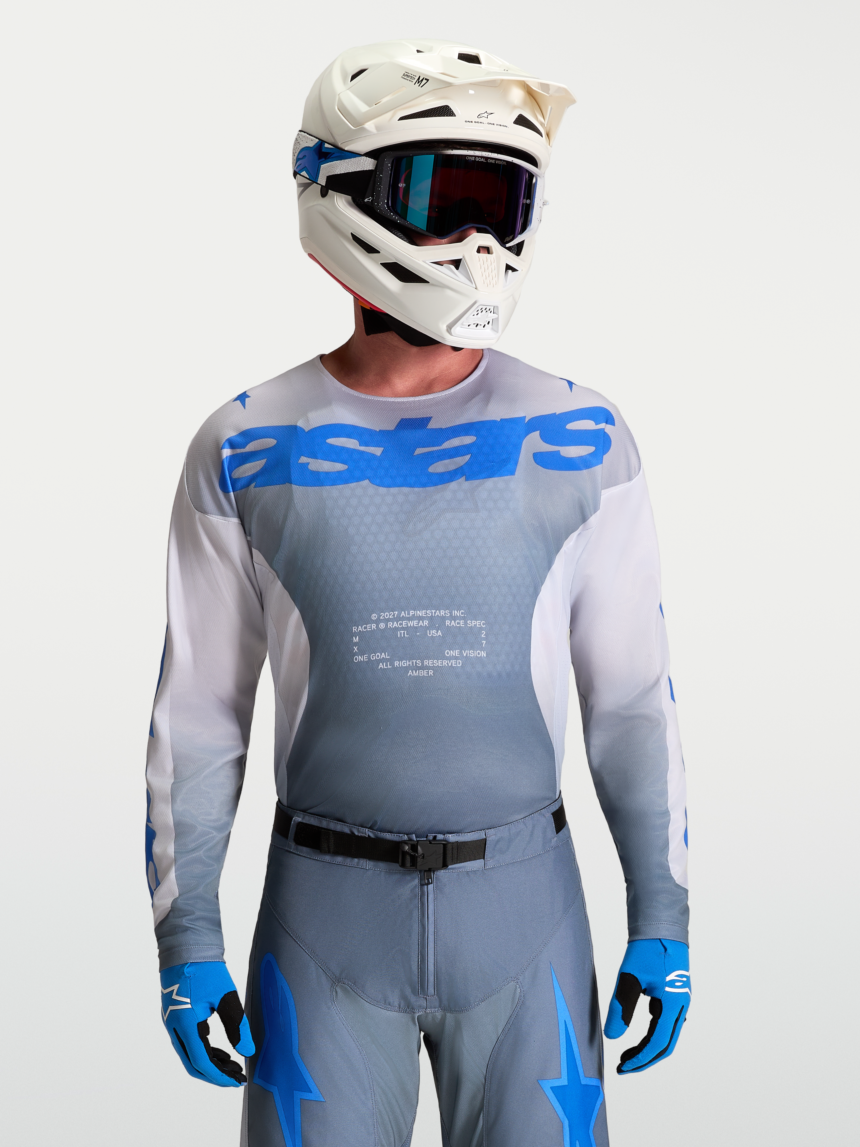 Alpinestars Racer Amber Trikot, Motocross-Ausrüstung für Herren, Grau und UCLA Blau, mit weißem MX-Helm und Schutzbrille.