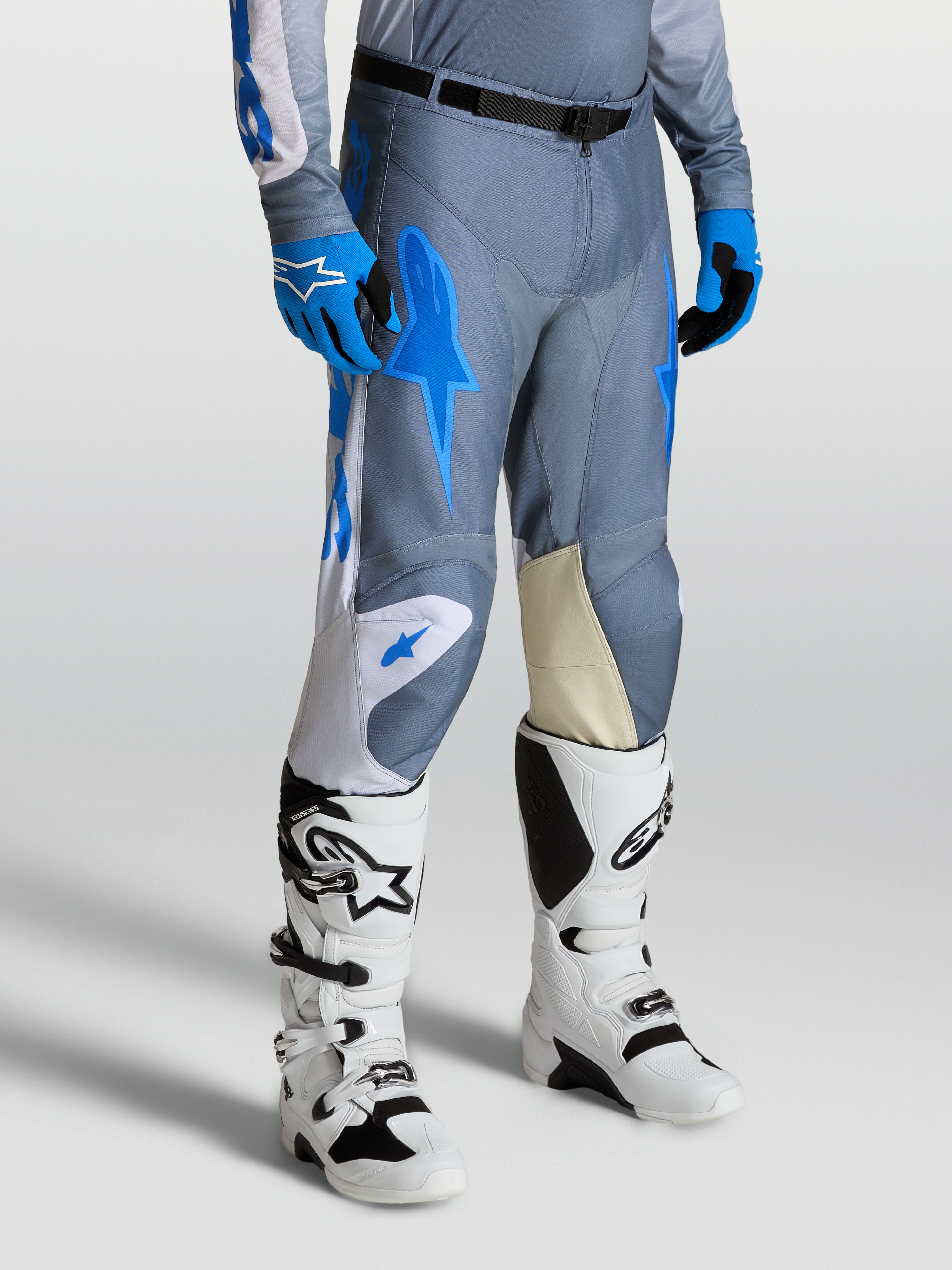 Alpinestars Racer Amber Hose, Motocrosshose für Herren, Grau und Blau, mit Knieeinsätzen aus Ziegenleder und weißen Techstar Stiefeln.