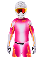 Alpinestars Limited Edition Supertech AFD MIG Jersey, Pink Fluo Weißes Motocross-Trikot, mit einem leuchtenden Farbverlauf und orangefarbenen Stern-Logos, getragen als komplettes Rennset mit passender Hose, weißem Helm und roter Schutzbrille, professionelle Dirt-Riding-Bekleidung