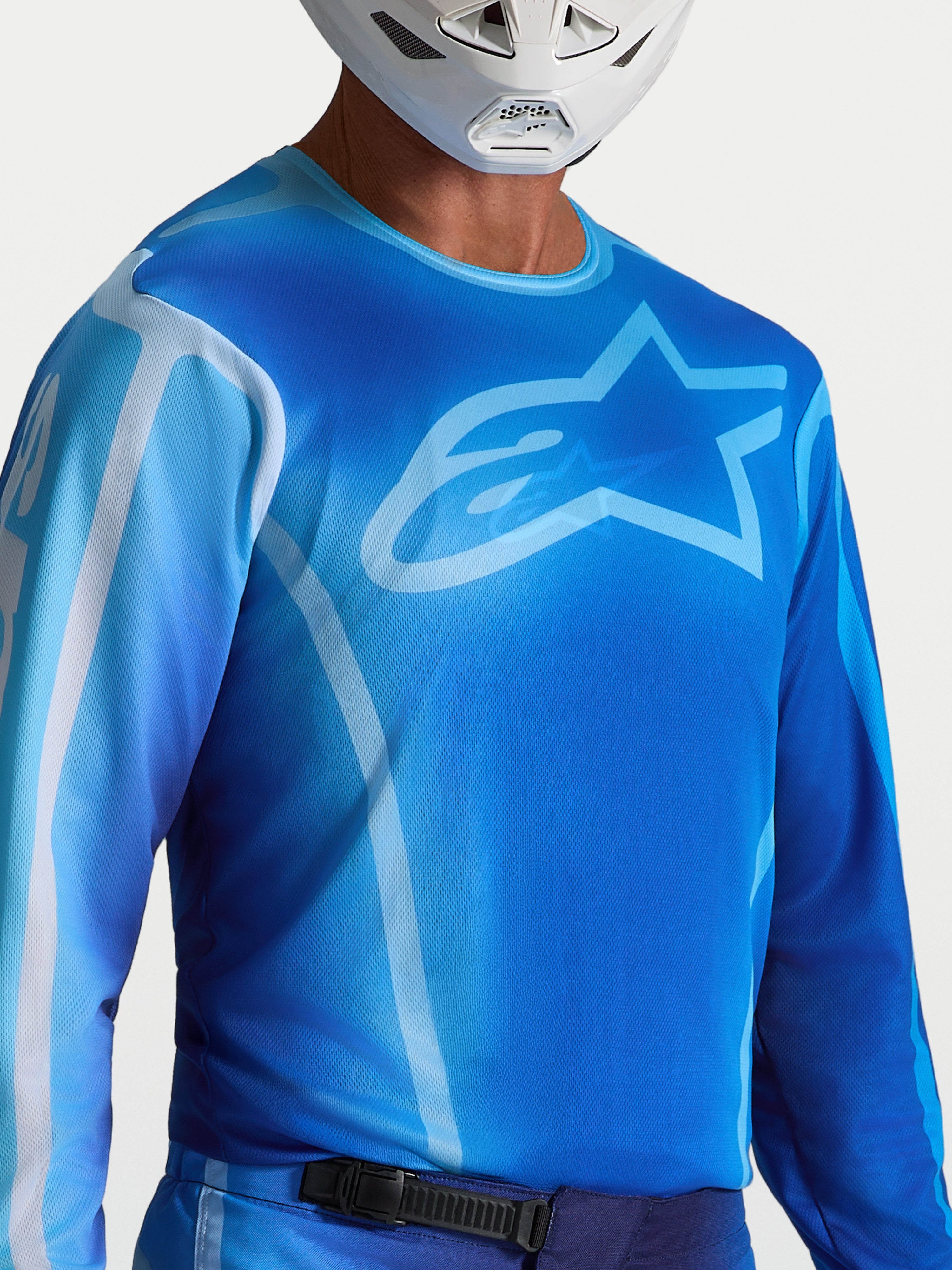 Alpinestars Fluid Kepler Trikot, blaues Motocross-Performance-Jersey mit sportlicher Passform, feuchtigkeitsableitendes Polygewebe, Alpinestars-Logo auf der Brust, getragen von einem Fahrer mit weißem Helm.