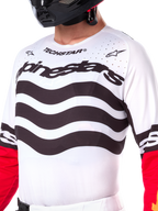 Alpinestars Limited Edition Techstar Deep Trikot, weißes Motocross-Trikot mit wellenförmigen schwarzen horizontalen Streifen und roten Ärmeln, Alpinestars- und Techstar-Branding, kleine lasergeschnittene Perforationen im oberen Brustbereich zur Belüftung, sportliche Offroad-Ausrüstung