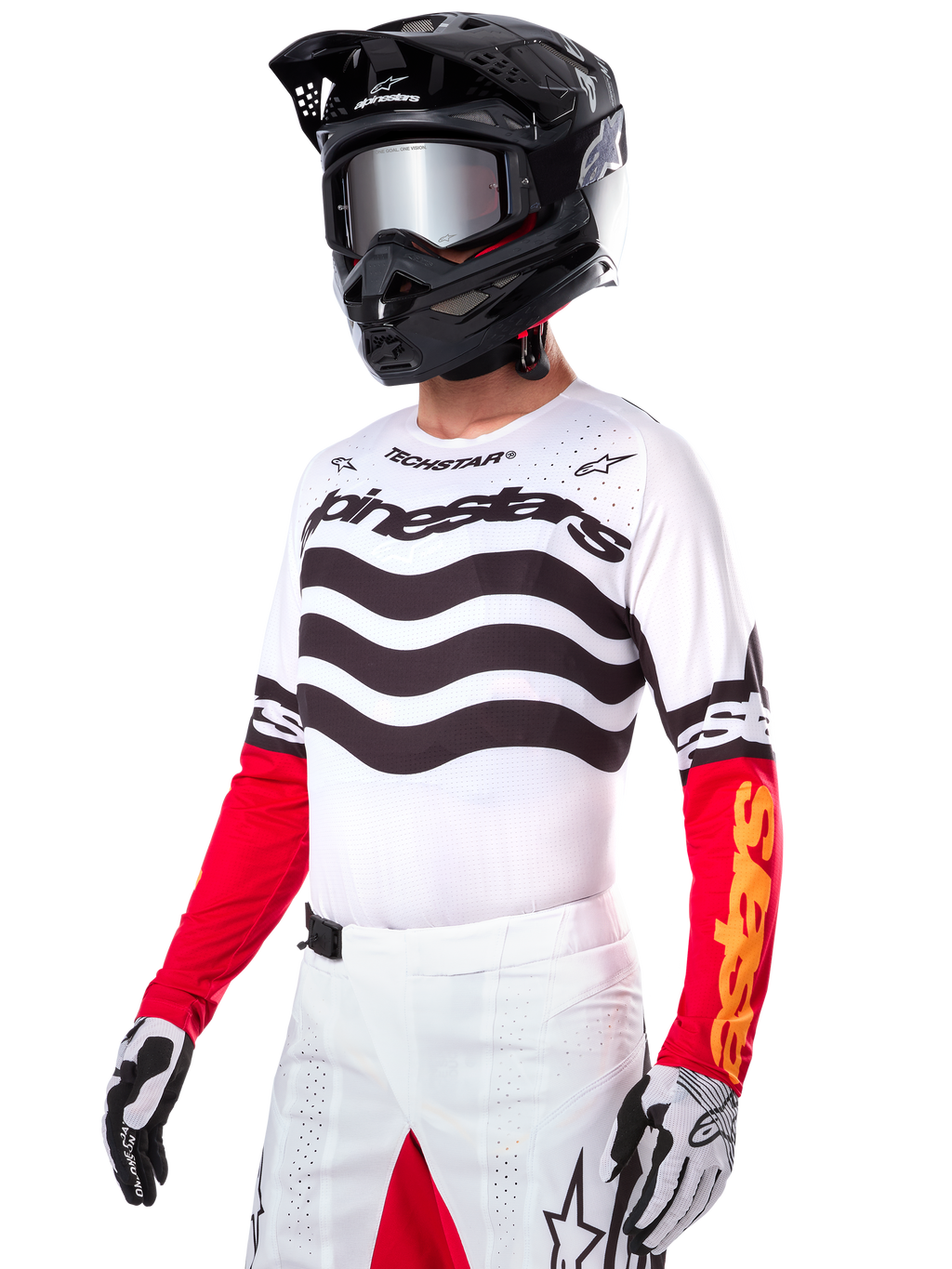 Motocross-Fahrer im Alpinestars Limited Edition Techstar Deep Jersey, weißes Trikot mit schwarzen Wellenstreifen und roten Unterärmeln, kombiniert mit schwarzem Helm, verspiegelter Brille, weiß-schwarzen Handschuhen und weißer Rennsport-Hose, Performance-Motocross-Outfit.