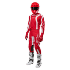 Motocross-Fahrer in kompletter Rennausrüstung, Alpinestars 2024 Fluid Lurv Jersey in Mars-Rot und Weiß, passende rote Hose mit weißen Akzenten, roter Helm, rote Handschuhe und weiß-schwarze Stiefel, abgestimmtes Outfit für den Offroad-Rennsport
