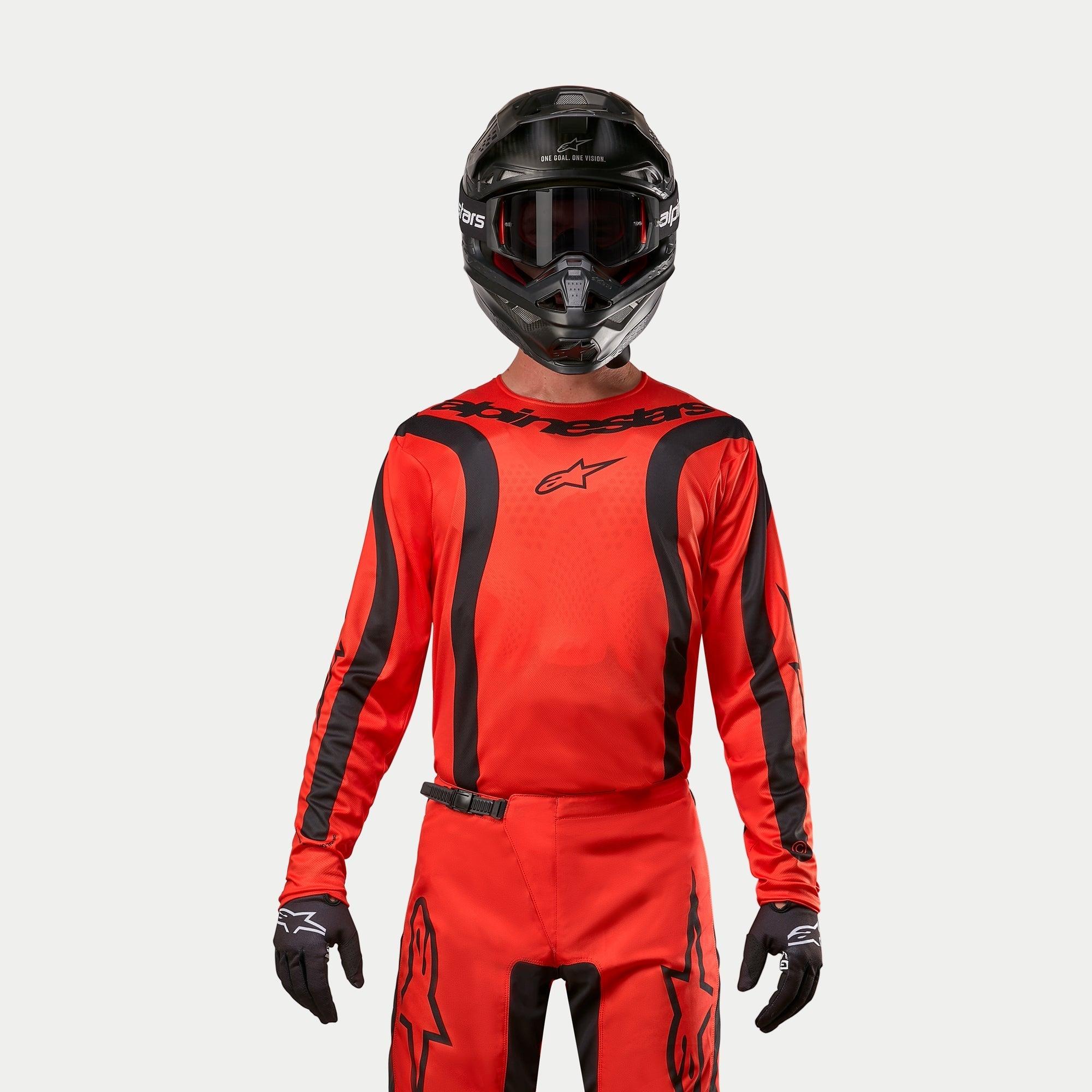 Motocross-Fahrer im Alpinestars 2024 Fluid Lurv Trikot, Hot Orange und Schwarz, passender Motocross-Hose, schwarzem Helm mit Brille und schwarzen Handschuhen, abgestimmte Ausrüstung für Offroad-Rennen