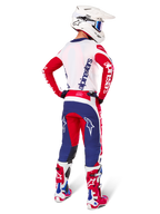Motocross-Fahrer in der Rückansicht, Alpinestars Limited Edition Techstar Fortitude Jersey in leuchtendem Rot, Weiß und Blau, passende technische Hose mit Stern-Logos, weißer Helm mit Schutzbrille und rot-weiße Stiefel, komplette koordinierte Ausrüstung für Offroad-Rennen