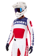 Motocross-Fahrer im Alpinestars Limited Edition Techstar Fortitude Jersey, Bright Red White Blue, mit weißem Helm, blauer Brille und passender Hose, Hochleistungs-Rennbekleidung für Offroad-Wettkämpfe