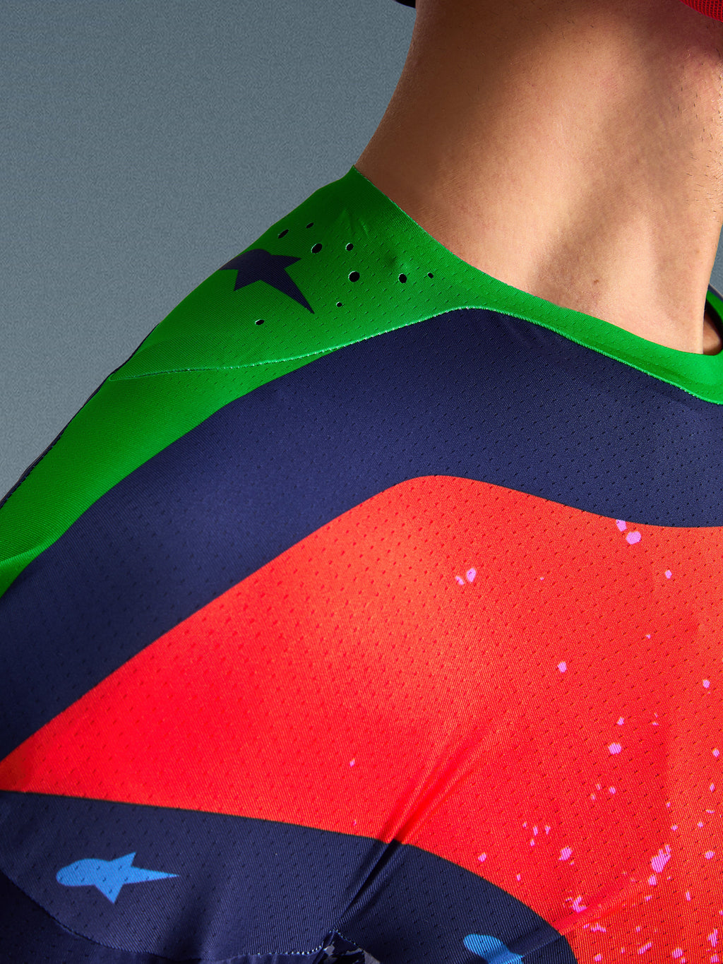 Nahaufnahme des Alpinestars Limited Edition Supertech Records Trikots, mehrfarbiges Design mit grüner Schulterpartie, marineblauen und roten Einsätzen, mit lasergeschnittenen Perforationen und atmungsaktivem Mesh-Gewebe für professionelle Motocross-Performance.