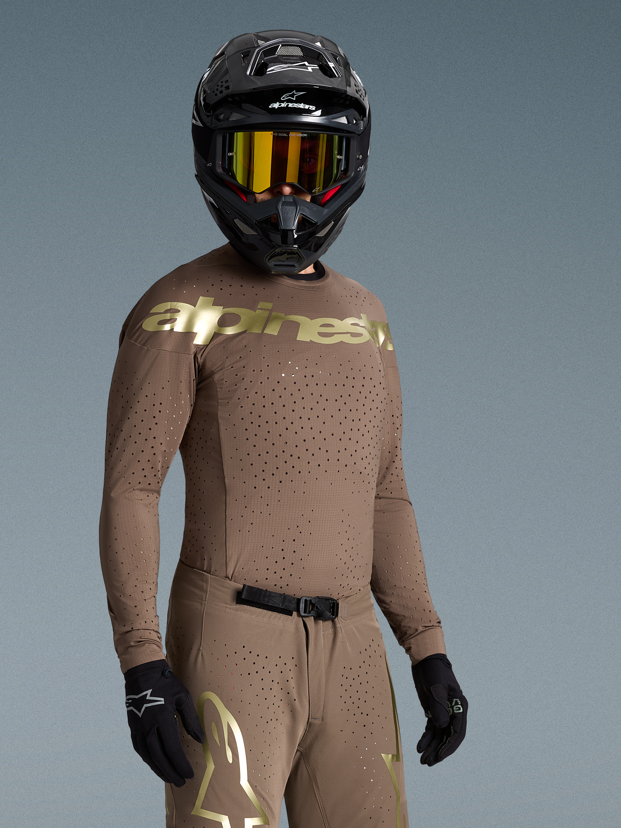 Alpinestars Supertech Air Gold Bekleidungsset, sandfarbenes MX-Outfit mit goldenen Logos und Laser-Cut-Belüftung.
