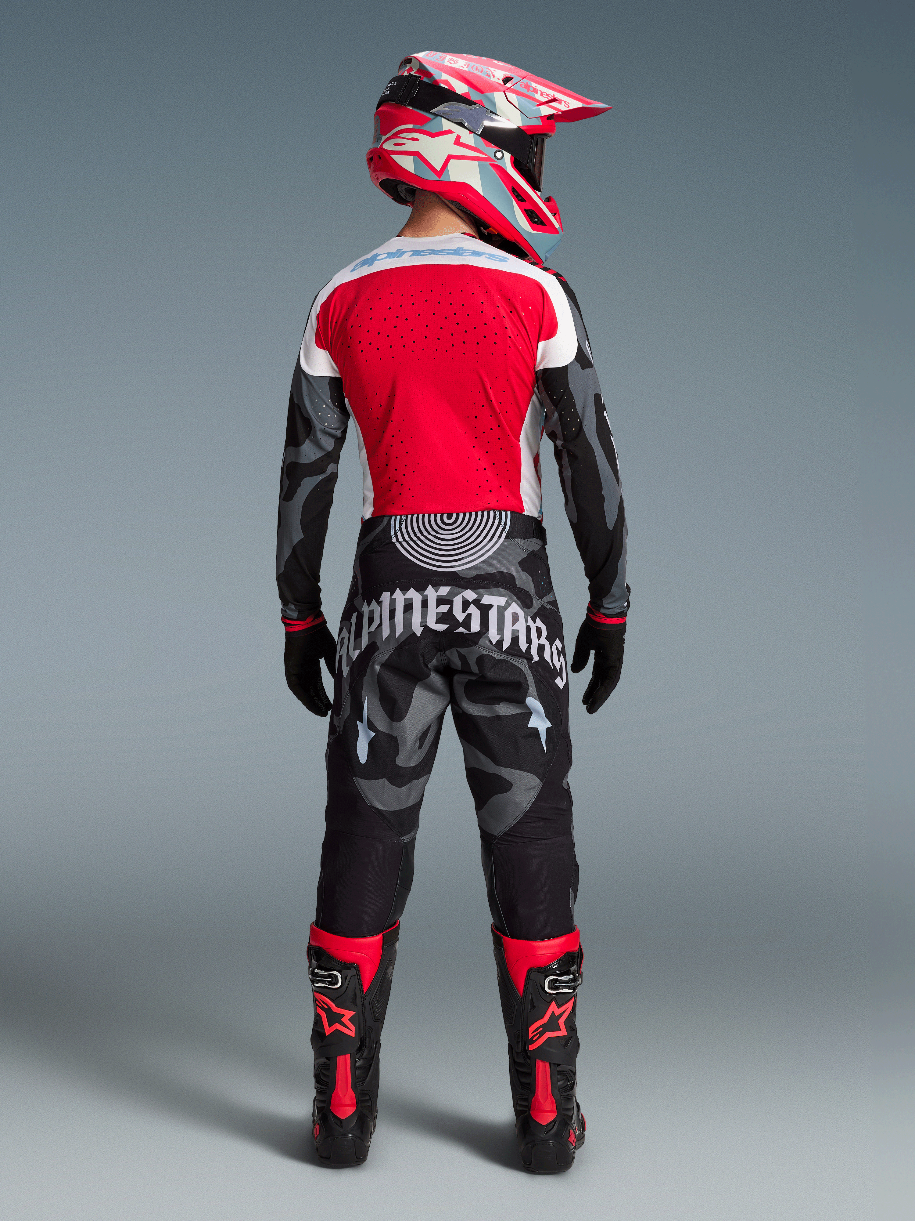Alpinestars Techstar Beast Coast MX-Ausrüstung, rotes Trikot und Camo-Hose mit passendem Helm und Stiefeln von hinten.