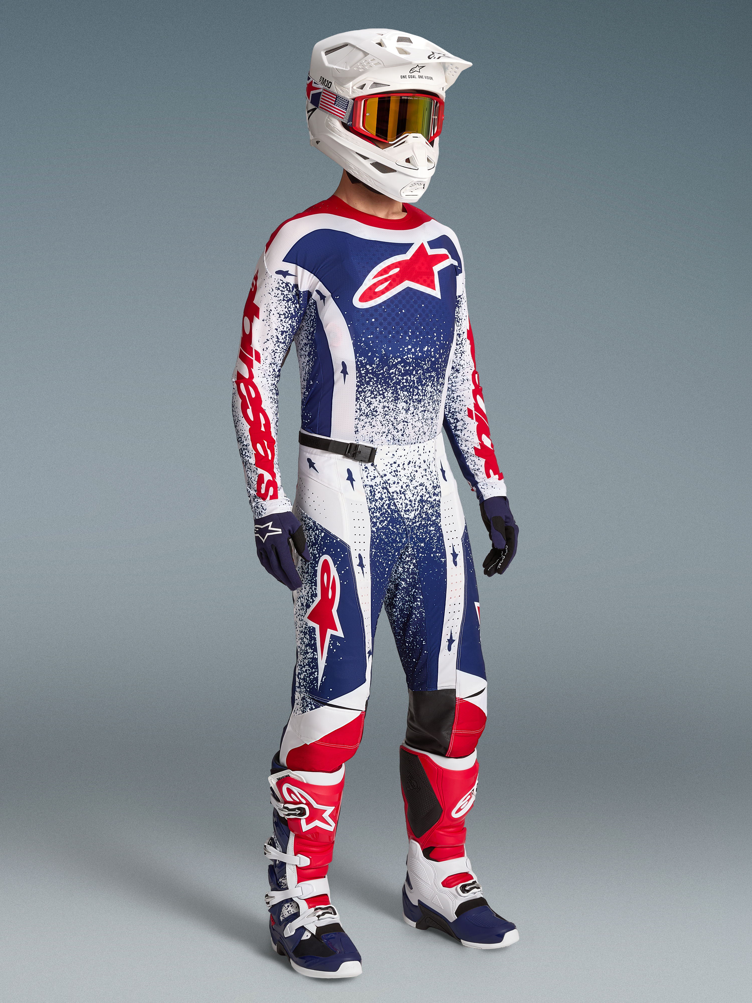 Alpinestars Limited Edition Techstar Unity men's motocross gear set in red, white, and blue with racing boots and helmet.