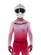 Motocross-Fahrer im Alpinestars 2024 Supertech Dade Jersey in Red Berry Lilac, passende Hose, weißer Helm mit schwarzer Brille und rote Handschuhe, professionelle Rennausrüstung mit pink-rotem Farbverlauf