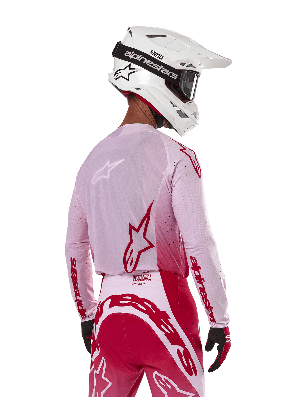 Motocross-Fahrer in der Rückansicht, trägt das Alpinestars 2024 Supertech Dade Jersey in Red Berry Lilac, mit atmungsaktiven Mesh-Panels und roten Alpinestars-Logos, kombiniert mit einer passenden rot-lilafarbenen Hose und einem weißen Alpinestars-Helm mit Brille, professionelle Offroad-Rennausrüstung