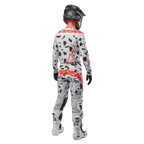 Motocross-Fahrer von hinten mit Alpinestars 2024 Techstar Rantera Trikot und passender Hose, Haze Gray Camo-Muster mit markanten roten Alpinestars-Logos, schwarzer Helm, weiß-schwarze Stiefel, schwarze Handschuhe, koordiniertes Motocross-Ausrüstungsset.