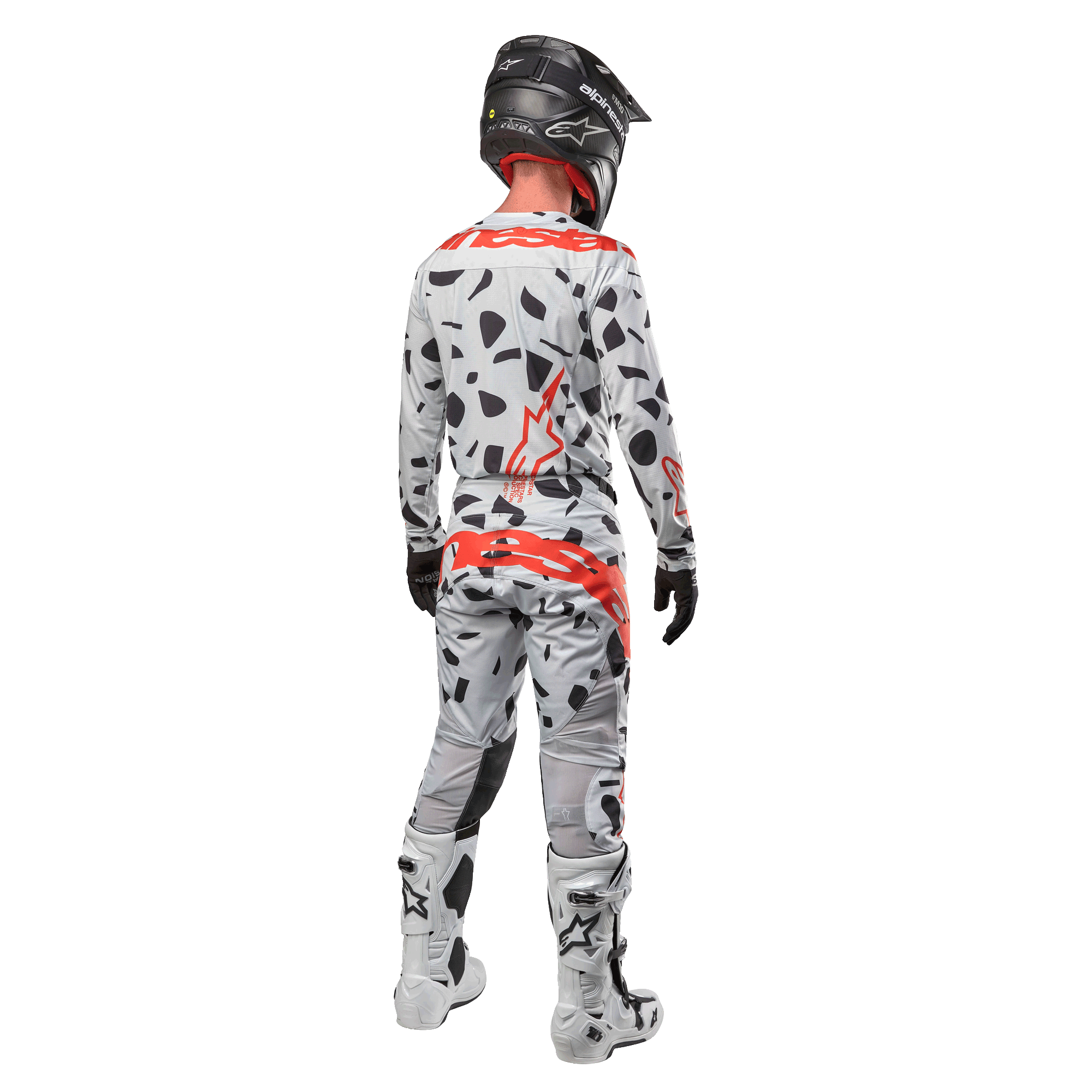 Motocross-Fahrer von hinten mit Alpinestars 2024 Techstar Rantera Trikot und passender Hose, Haze Gray Camo-Muster mit markanten roten Alpinestars-Logos, schwarzer Helm, weiß-schwarze Stiefel, schwarze Handschuhe, koordiniertes Motocross-Ausrüstungsset.