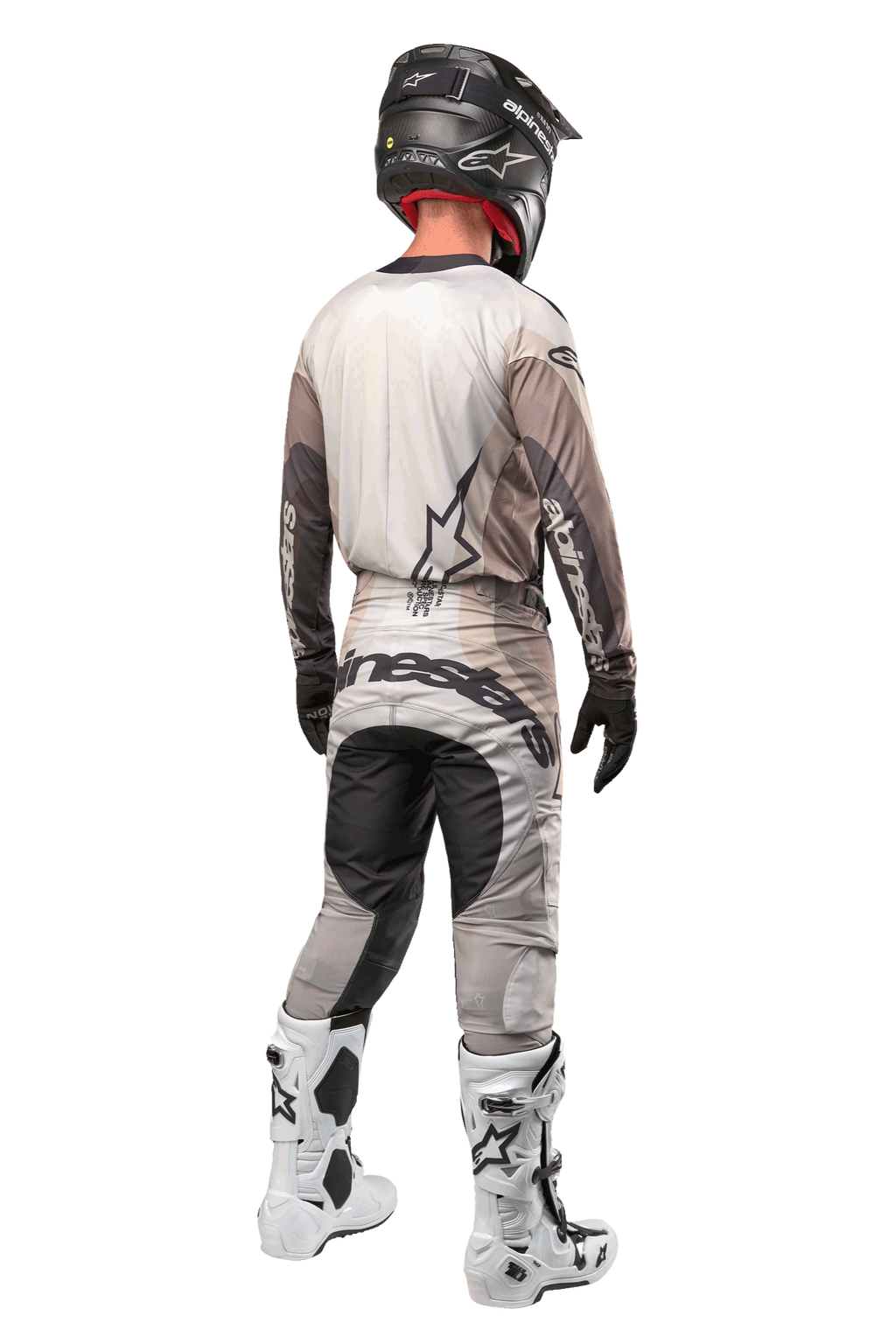 Motocross rider from the back wearing the 2024 Techstar Pneuma Jersey in Dark Sand Iron Dust Gray, matching motocross pants with bold branding, black helmet, and white racing boots, coordinated professional off-road gear.