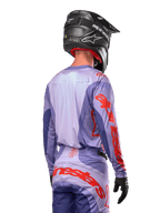 Alpinestars 2024 Techstar Ocuri Jersey, Motocross-Trikot, Lila und Hot Orange, Rückansicht eines Fahrers in passender Ausrüstung und schwarzem Helm, mit großem orangefarbenem Alpinestars-Schriftzug auf den Ärmeln und dem unteren Rücken